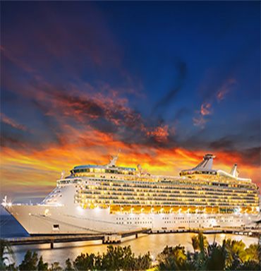 Cruise ship at sea under a colorful sunset sky