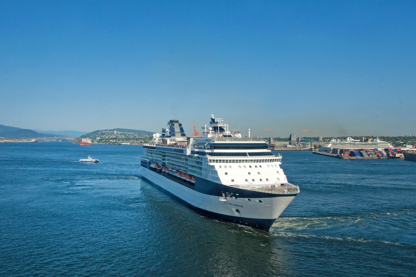 Cruise ship sailing out of port on calm blue water