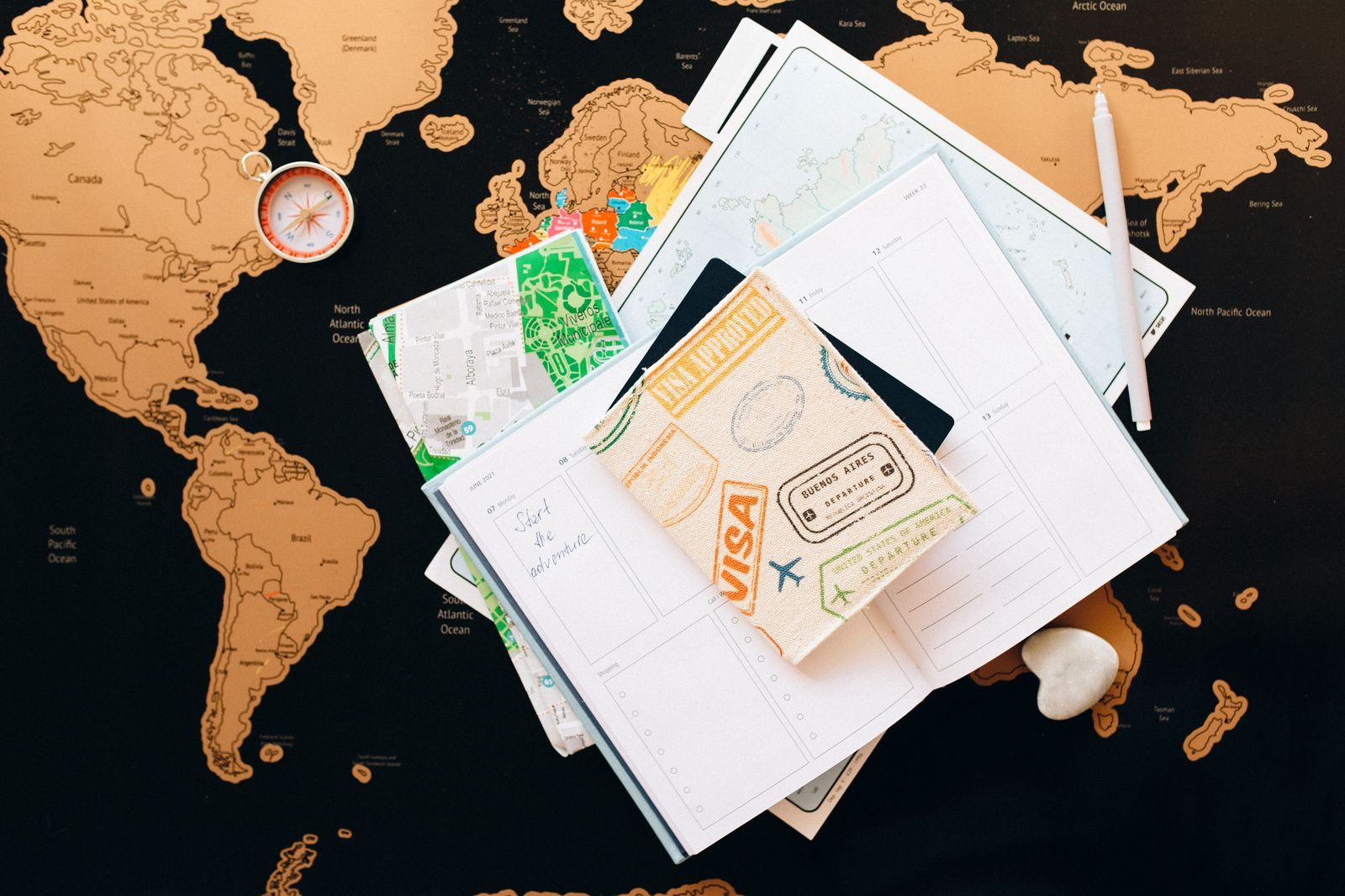 Travel planning flat lay: world map, compass, passport stamps and notebook