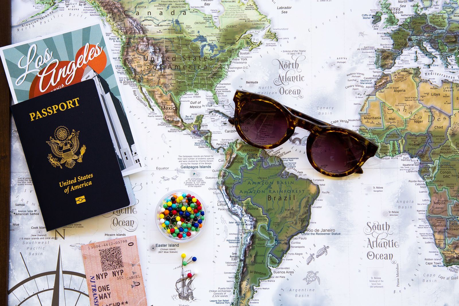 Passport, sunglasses and pins on a world map